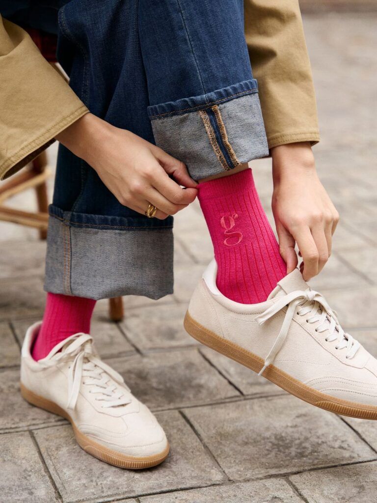 Photo d'une femme en train d'ajuster ses chaussettes rose fushia avec le monogramme G de Gambettes Box