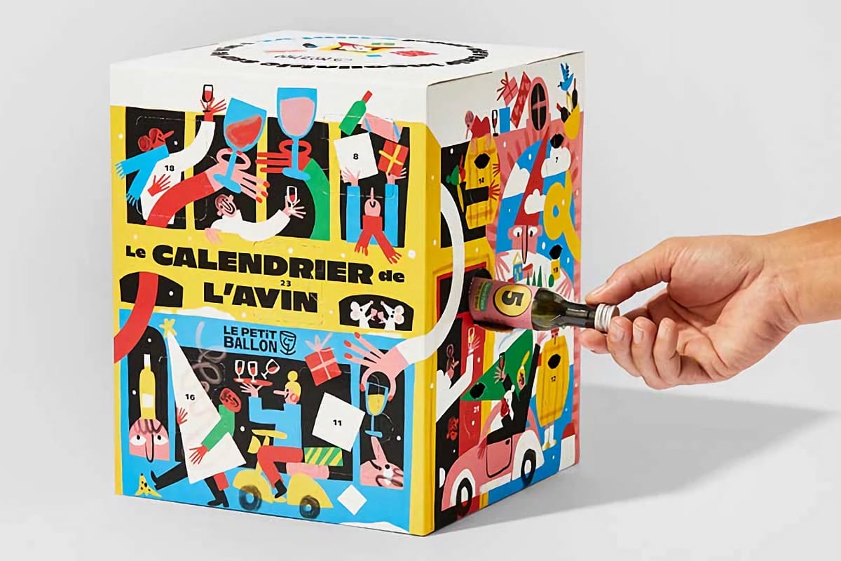 Main qui sort une petite bouteille numérotée du calendrier de l’Avent de vin au design coloré