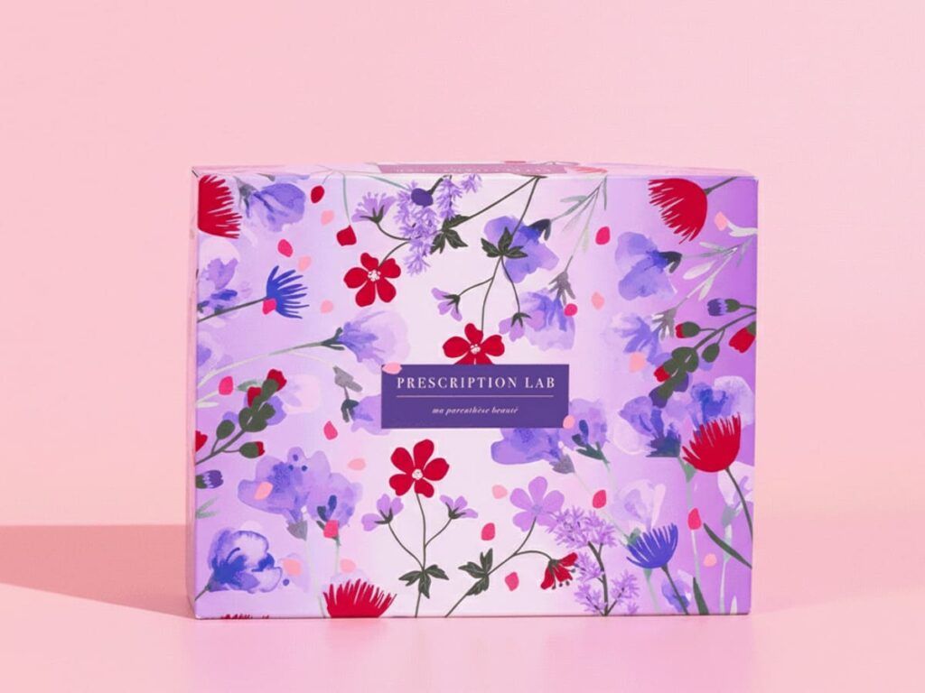 Design de la box Prescription Lab Just Love, illustrée de motifs floraux violets et rouges sur fond rose