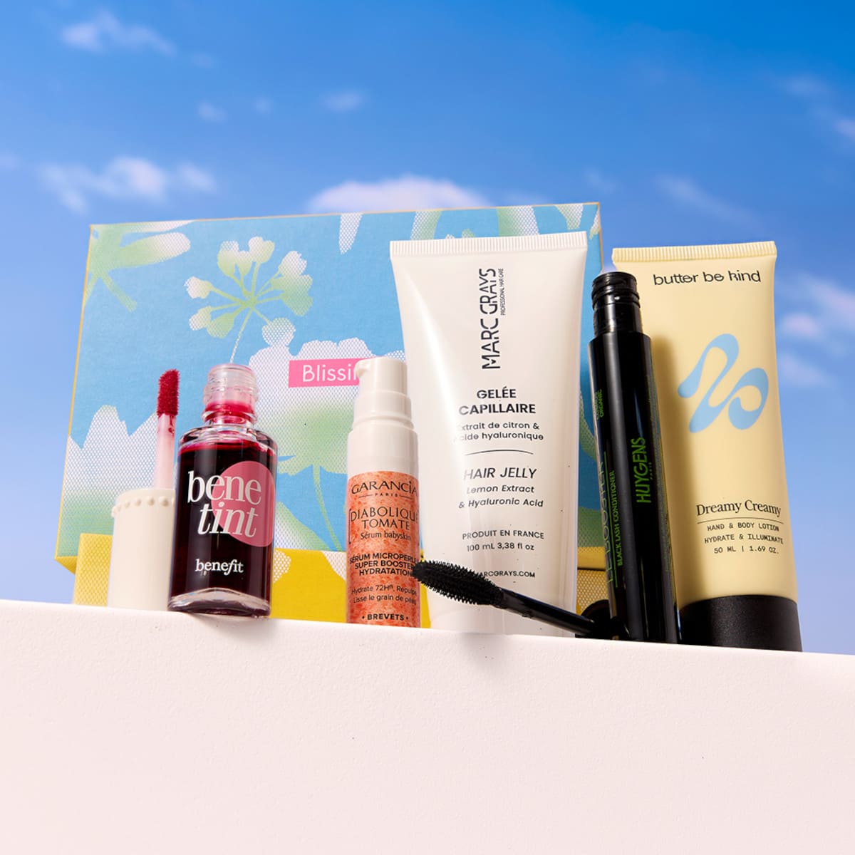 Produits beauté Blissim présentés devant le coffret printanier avec Bene Tint de Benefit, sérum Garancia et mascara Huygens