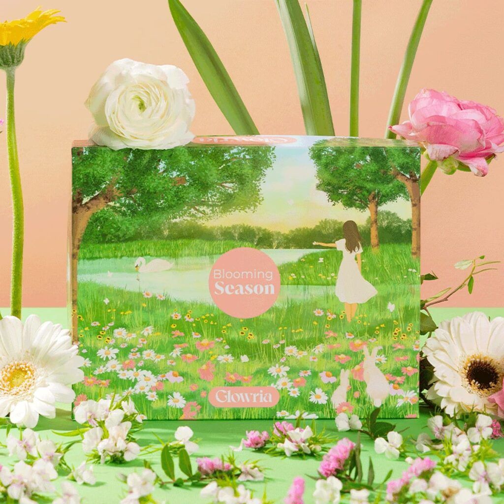 Design de la box Glowria Blooming Season avec illustration printanière, fleurs et paysage au bord de l’eau