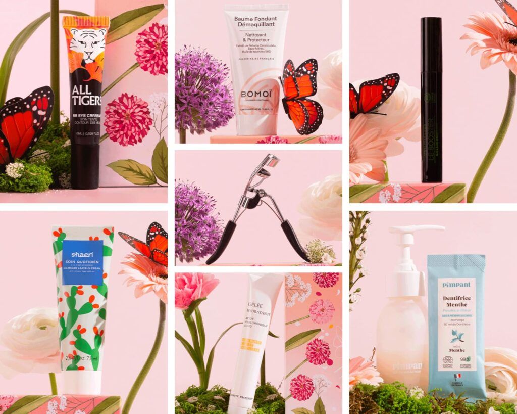Montage de cosmétiques incluant le mascara Huygens Le Booster, BB crème All Tigers, soin hydratant et recourbe-cils sur fond fleuri