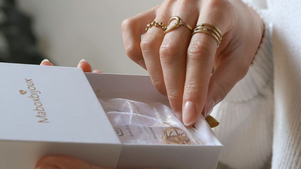 Ma Box Bijoux avec main ouvrant un coffret contenant des bijoux dorés