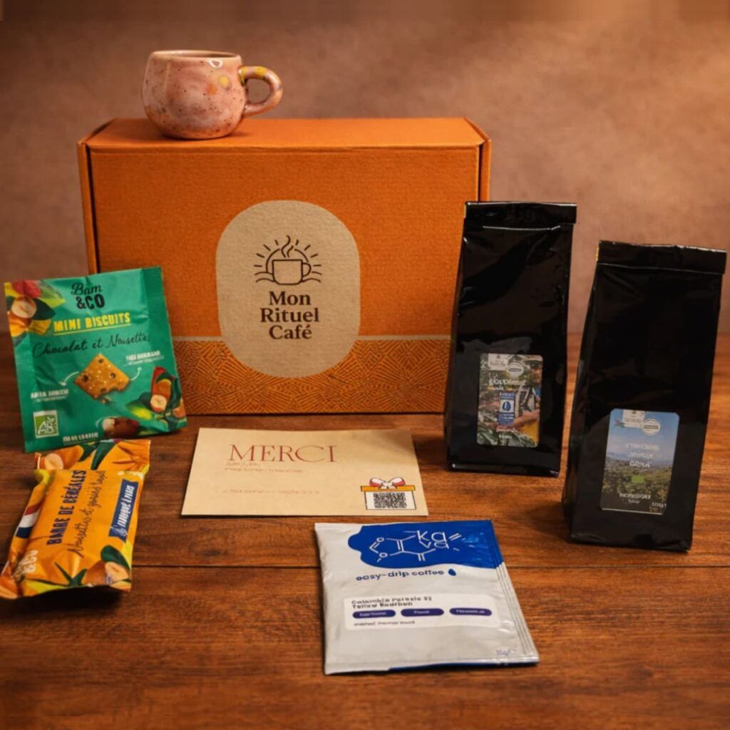 Coffret café avec deux sachets de café en grains, biscuits et café drip posé sur une table