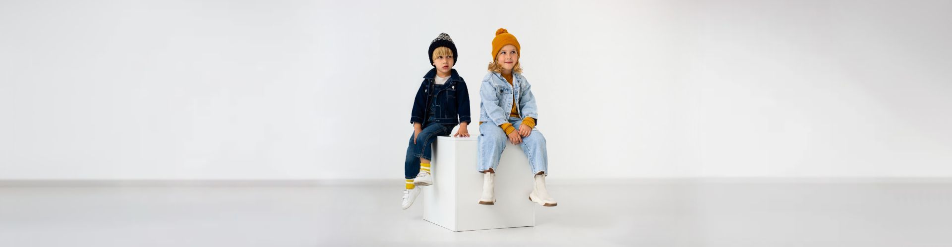 Image d’illustration de la catégorie box vêtements enfant, bébé et adolescent, avec deux enfants portant des tenues tendance assis sur un cube