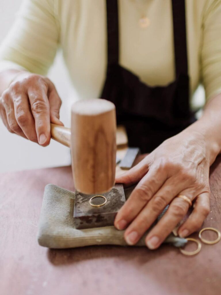 Atelier bijouterie Wecandoo montrant la fabrication artisanale d’une bague en métal avec un maillet