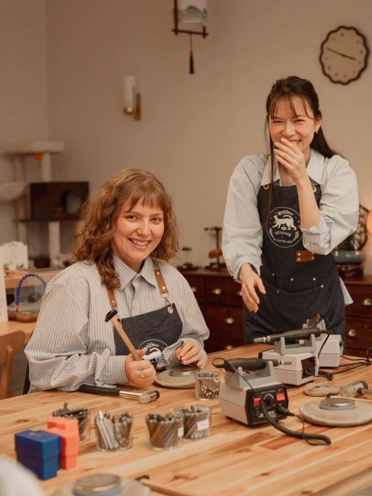 Atelier de création de bijoux avec deux participantes travaillant à un établi avec outils de bijoutier