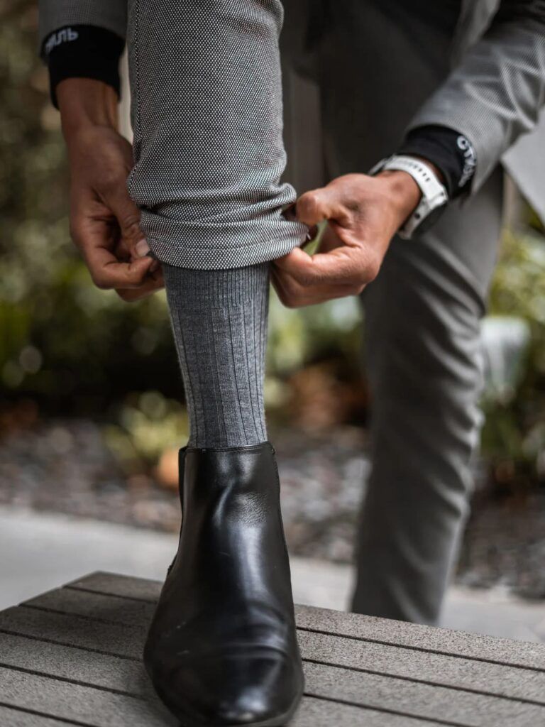 Gros plan sur une chaussette grise côtelée portée avec un pantalon habillé et une bottine noire