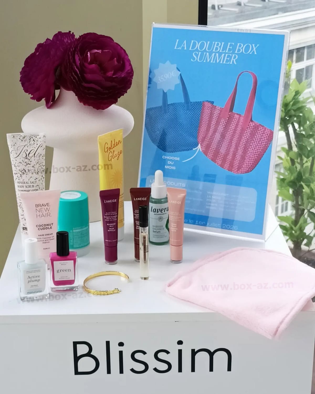Blissim juillet août 2026 spoiler complet avec les produits beauté, accessoires et sacs de la double box été présentés sur un présentoir