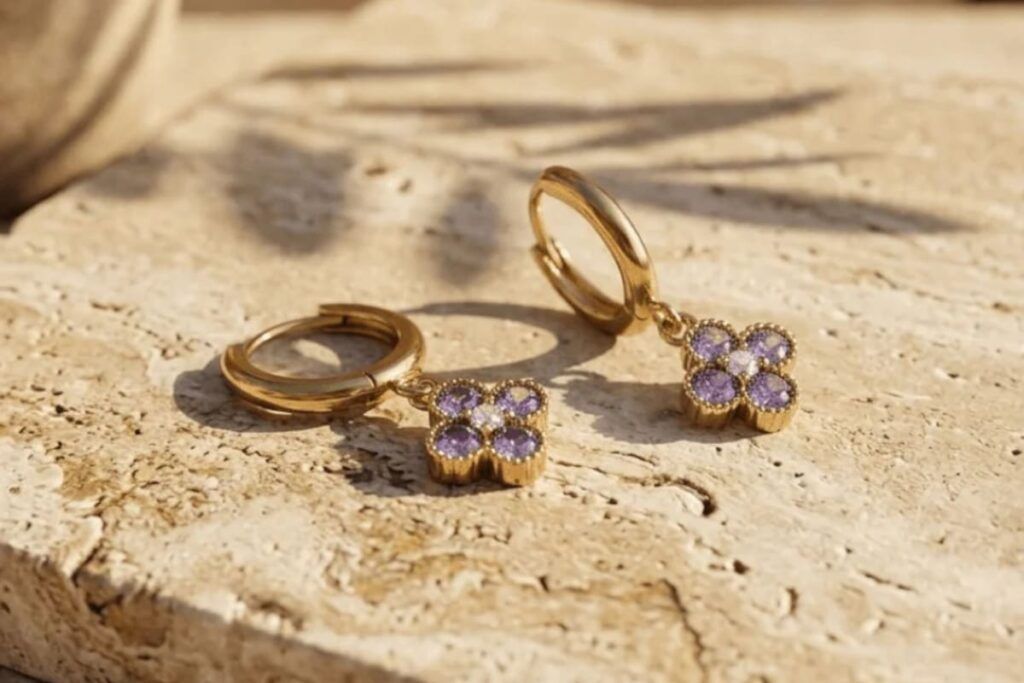 Boucles d'oreilles dorées en forme de fleur serties de pierres violettes, exemple de bijou reçu dans un abonnement bijoux