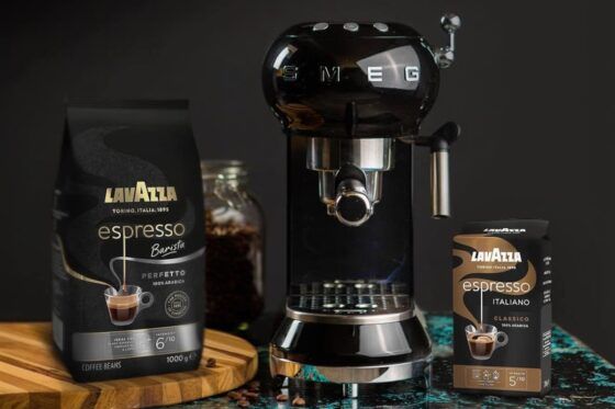 Abonnement café Lavazza avec machine à café SMEG noire et cafés Espresso Barista présentés sur une table