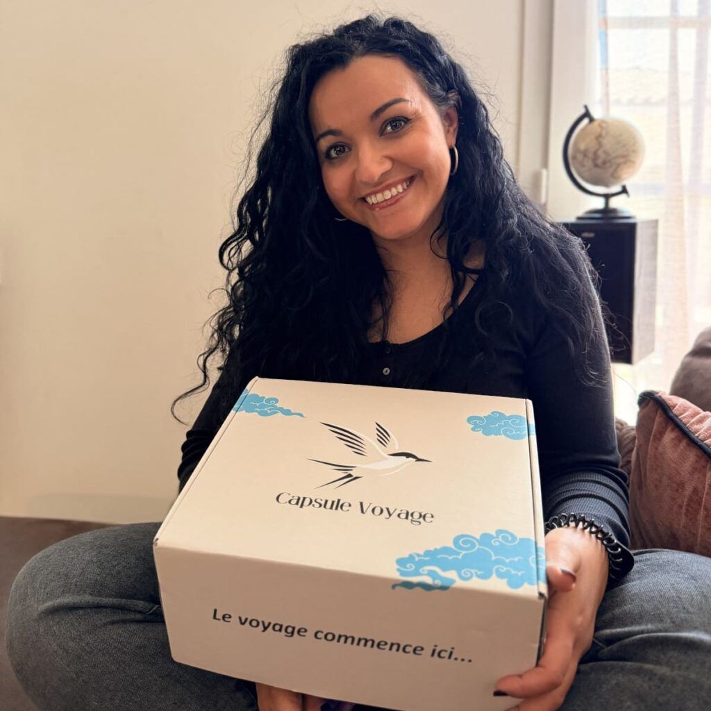 Femme souriante tenant une box de voyage immersive sur ses genoux