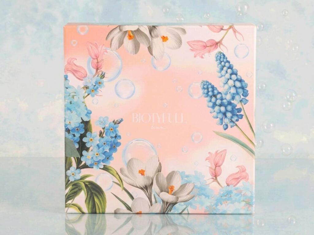 Design de la box « Bulles de Douceur », un coffret rose pastel illustré de fleurs bleues, blanches et de bulles transparentes